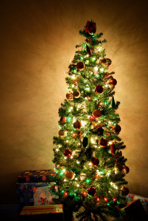 small christmas tree with green red and white lights and bulb ornaments with presents under the tree