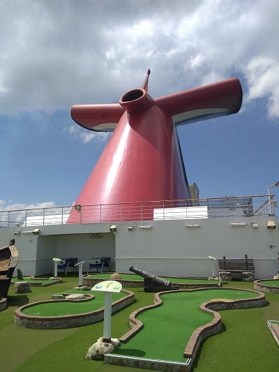 mini golf course on a cruise ship with carnival whale tail red funnel in background